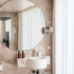Salle de bains de la Chambre Classique de l’Hôtel Barnett à Paris avec vasque, miroir éclairé et revêtement en pierre naturelle.
