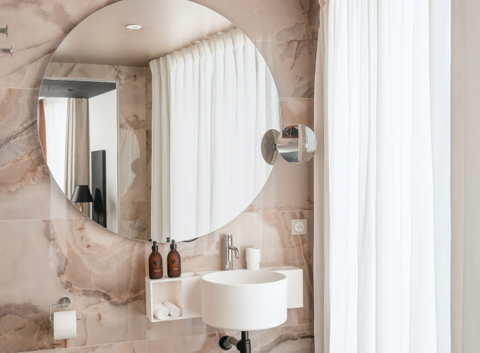 Salle de bains de la Chambre Classique de l’Hôtel Barnett à Paris avec vasque, miroir éclairé et revêtement en pierre naturelle.