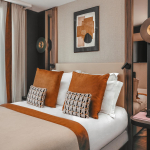 Chambre Classique de l’Hôtel Barnett à Paris avec lit double, coussins terracotta et œuvres d’art contemporaines.