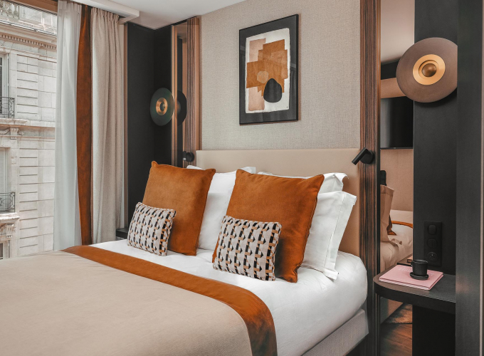 Chambre Classique de l’Hôtel Barnett à Paris avec lit double, coussins terracotta et œuvres d’art contemporaines.