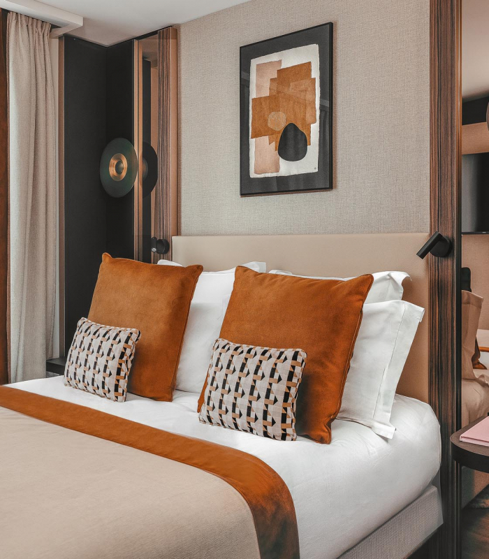 Chambre Classique de l’Hôtel Barnett à Paris avec lit double, coussins terracotta et œuvres d’art contemporaines.