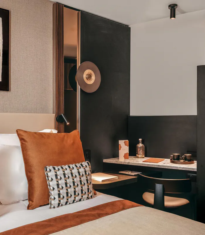 Chambre Classique de l’Hôtel Barnett à Paris avec lit double, coussins terracotta et œuvres d’art contemporaines.