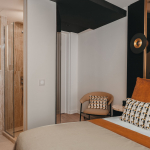 Chambre Cosy de l’Hôtel Barnett à Paris avec lit double, coussins terracotta et salle de bains ouverte en pierre.