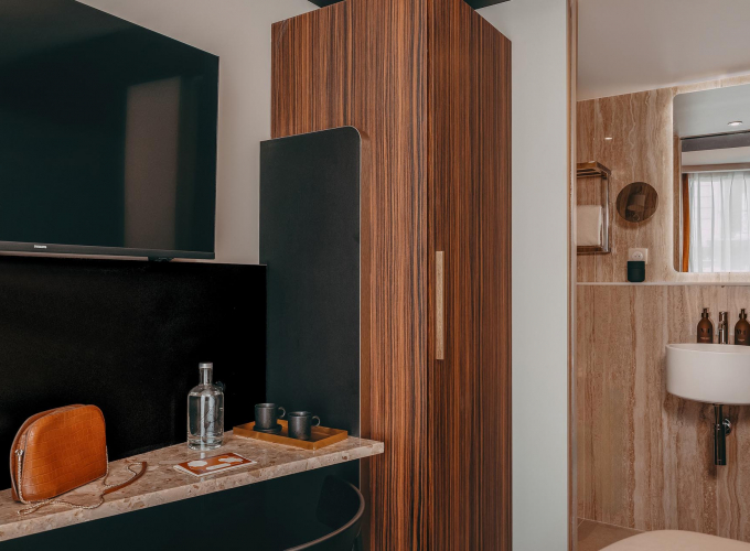 Salle de bains de la Chambre Cosy de l’Hôtel Barnett à Paris avec vasque, miroir et revêtement en pierre.