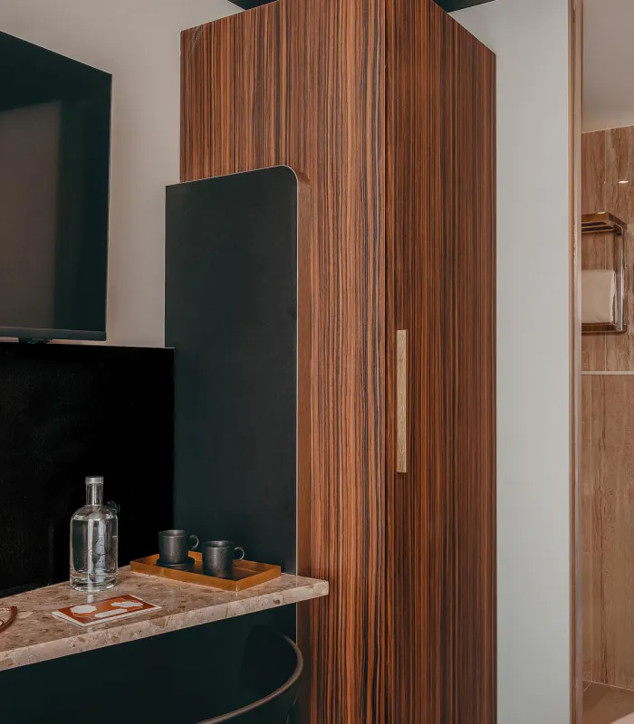 Salle de bains de la Chambre Cosy de l’Hôtel Barnett à Paris avec vasque, miroir et revêtement en pierre.