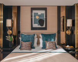 Chambre Supérieure de l’Hôtel Barnett à Paris avec lit double, coussins bleu canard, détails dorés et œuvre d’art contemporaine.