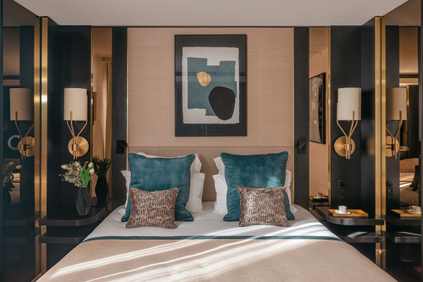 Chambre Supérieure de l’Hôtel Barnett à Paris avec lit double, coussins bleu canard, détails dorés et œuvre d’art contemporaine.