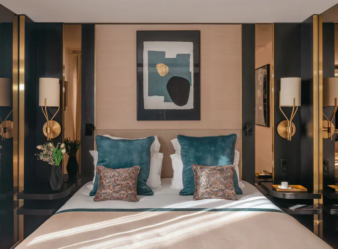 Chambre Supérieure de l’Hôtel Barnett à Paris avec lit double, coussins bleu canard, détails dorés et œuvre d’art contemporaine.