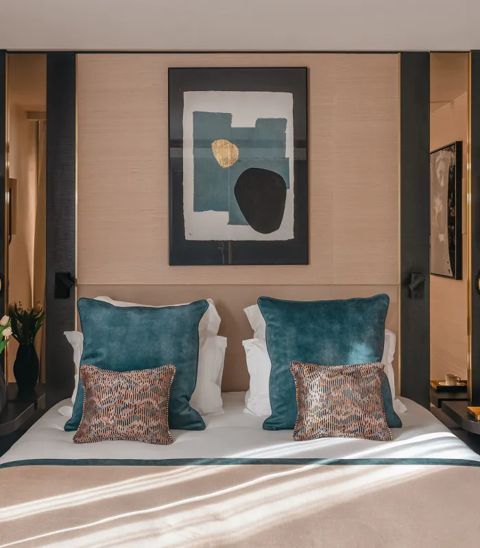 Chambre Supérieure de l’Hôtel Barnett à Paris avec lit double, coussins bleu canard, détails dorés et œuvre d’art contemporaine.