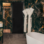 Salle de bains de la Chambre Prestige avec balcon de l’Hôtel Barnett à Paris avec baignoire îlot, marbre noir veiné et peignoirs.