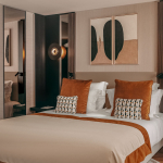 Chambre Deluxe de l’Hôtel Barnett à Paris avec lit double, coussins terracotta, miroirs et œuvres d’art contemporaines.