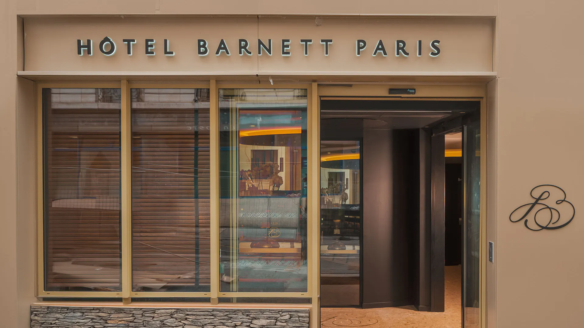 Façade de l’Hôtel Barnett à Paris avec entrée vitrée et enseigne lumineuse Hôtel Barnett Paris.