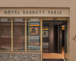 Façade de l’Hôtel Barnett à Paris avec entrée vitrée et enseigne lumineuse Hôtel Barnett Paris.