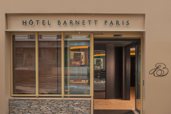 Façade de l’Hôtel Barnett à Paris avec entrée vitrée et enseigne lumineuse Hôtel Barnett Paris.