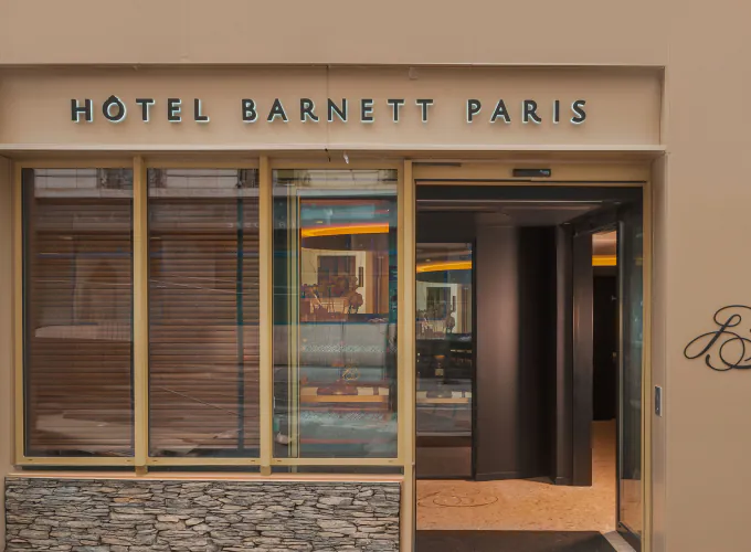 Façade de l’Hôtel Barnett à Paris avec entrée vitrée et enseigne lumineuse Hôtel Barnett Paris.