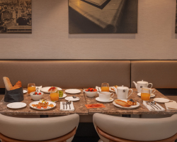 Table de petit-déjeuner de l’Hôtel Barnett à Paris avec viennoiseries, fruits frais, jus et boissons chaudes.