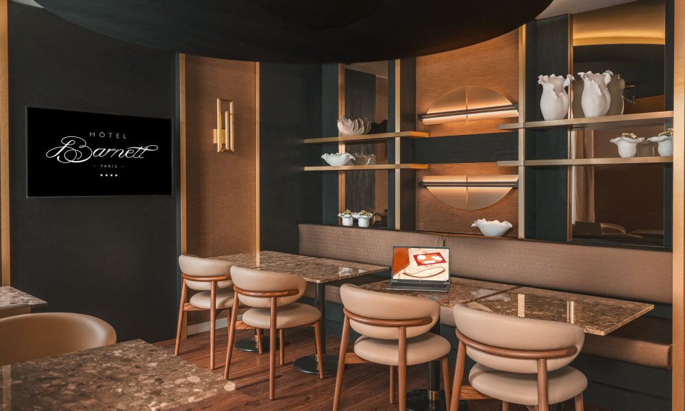 Sala de reuniões do Hôtel Barnett em Paris com mesas em pedra, cadeiras, ecrã e computador portátil.