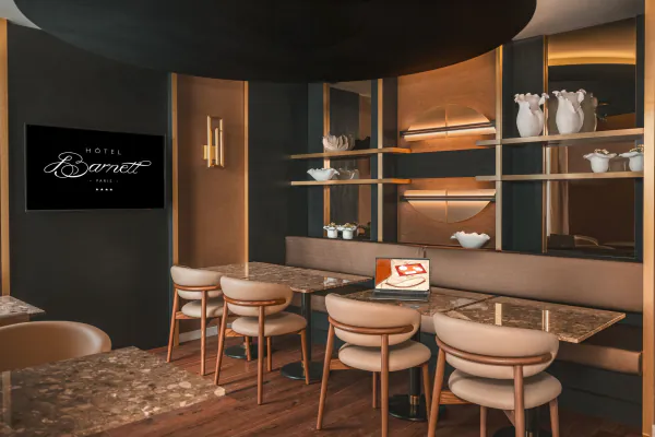 Salle de réunion de l’Hôtel Barnett à Paris avec tables en pierre, fauteuils, écran et ordinateur portable.