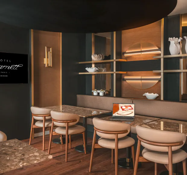 Sala de reuniões do Hôtel Barnett em Paris com mesas em pedra, cadeiras, ecrã e computador portátil.
