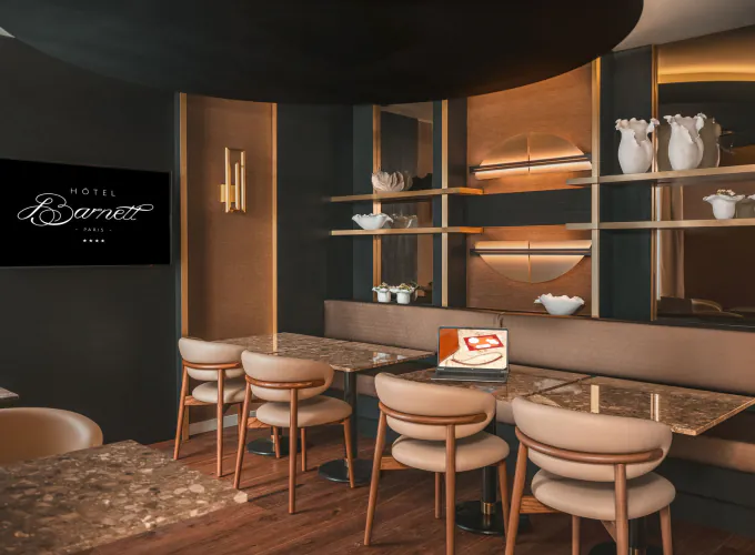 Salle de réunion de l’Hôtel Barnett à Paris avec tables en pierre, fauteuils, écran et ordinateur portable.