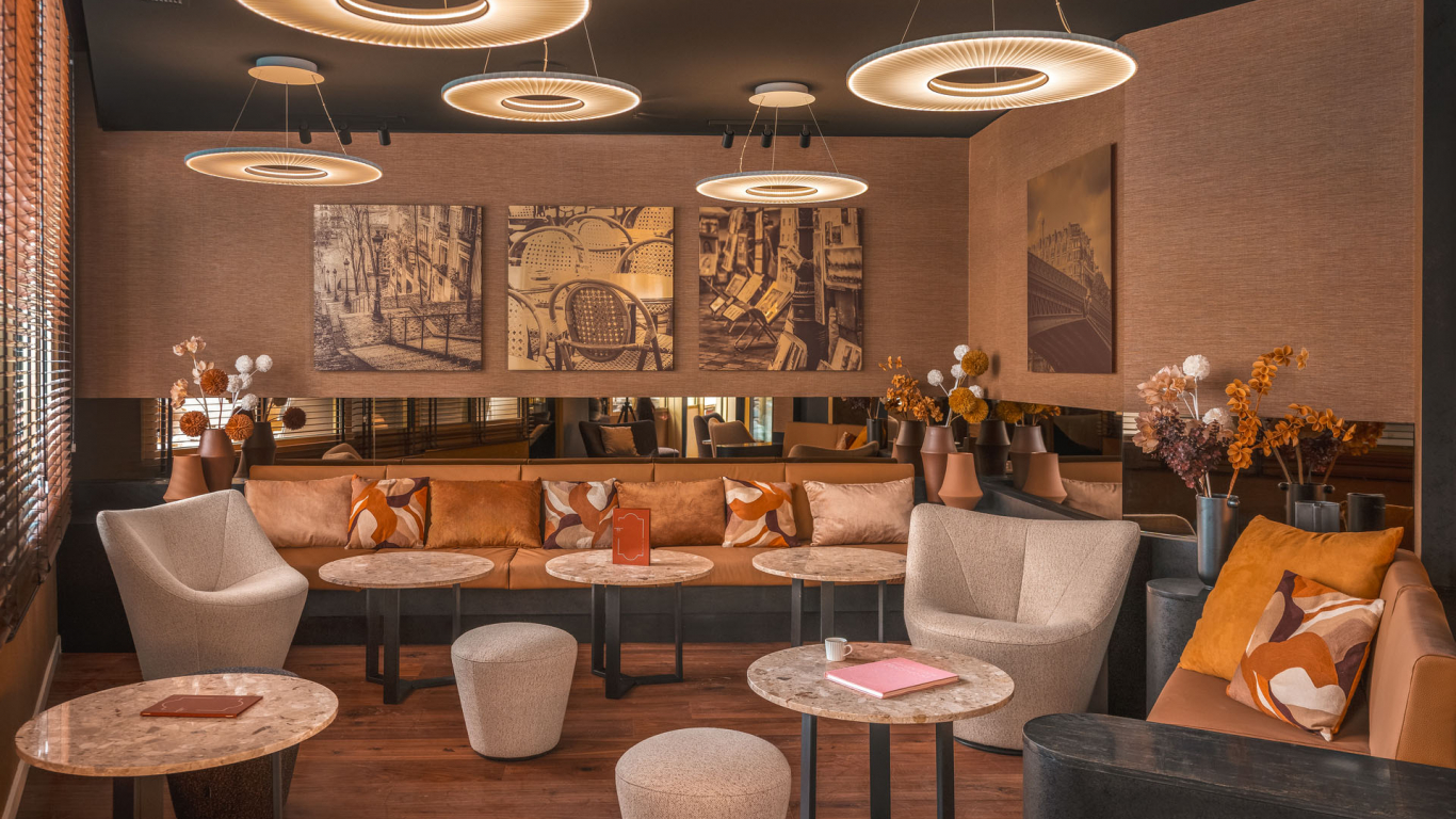 Lobby de l’Hôtel Barnett à Paris avec canapés, fauteuils, tables en pierre et luminaires suspendus contemporains.