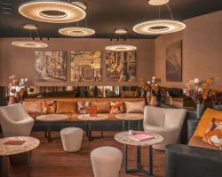 Lobby de l’Hôtel Barnett à Paris avec canapés, fauteuils, tables en pierre et luminaires suspendus contemporains.