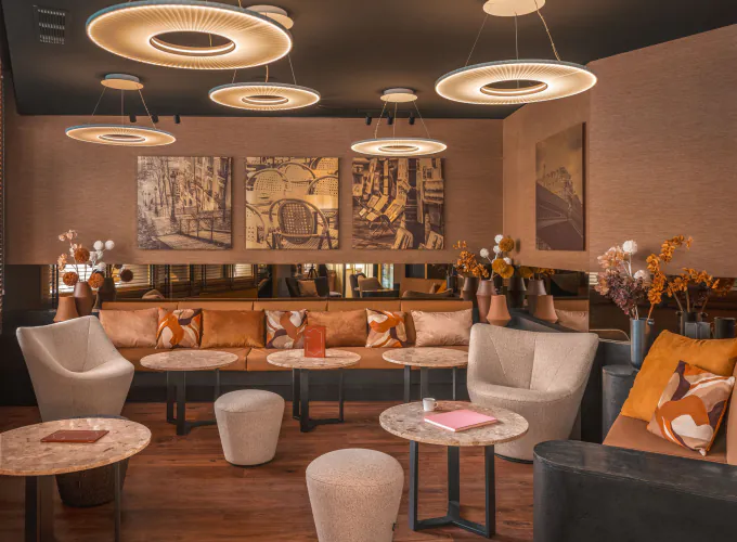 Lobby de l’Hôtel Barnett à Paris avec canapés, fauteuils, tables en pierre et luminaires suspendus contemporains.