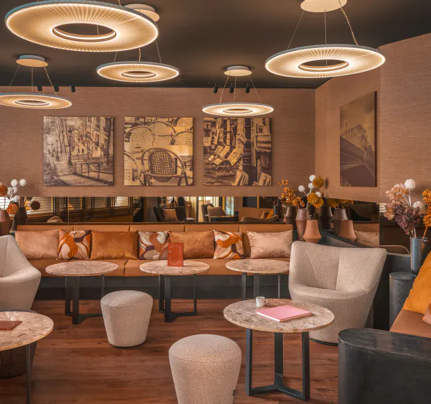 Lobby at Hôtel Barnett in Paris with sofas, armchairs, stone tables and contemporary pendant lights.