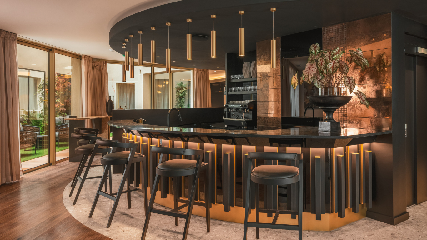 Bar de l’Hôtel Barnett à Paris avec comptoir en pierre, tabourets hauts et éclairage chaleureux.