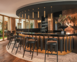 Bar de l’Hôtel Barnett à Paris avec comptoir en pierre, tabourets hauts et éclairage chaleureux.