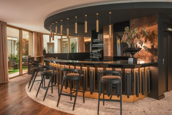 Bar de l’Hôtel Barnett à Paris avec comptoir en pierre, tabourets hauts et éclairage chaleureux.