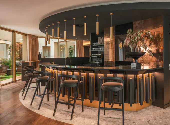 Bar de l’Hôtel Barnett à Paris avec comptoir en pierre, tabourets hauts et éclairage chaleureux.