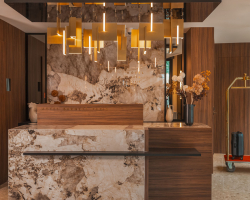 Réception de l’Hôtel Barnett à Paris avec comptoir en pierre et bois, luminaires dorés et décoration florale.