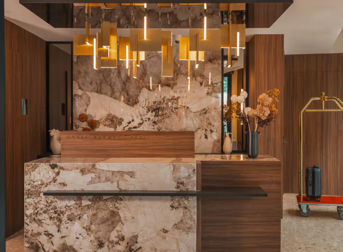 Réception de l’Hôtel Barnett à Paris avec comptoir en pierre et bois, luminaires dorés et décoration florale.